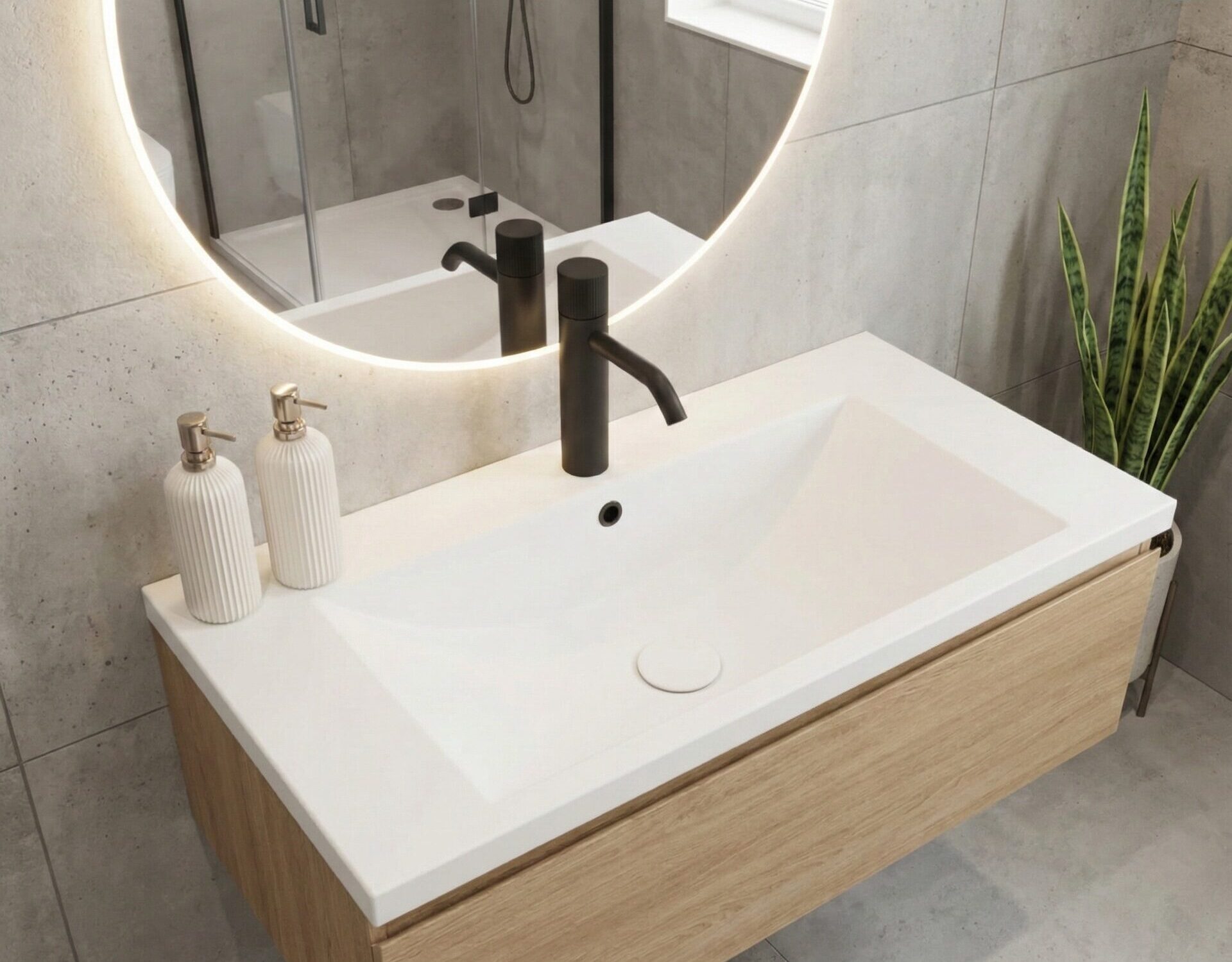 A bright, minimalist bathroom with a light speckled Glacier White Corian countertop and integrated sink. The design features a matte black faucet, a round backlit mirror, and a wooden shelf, creating a clean and airy atmosphere