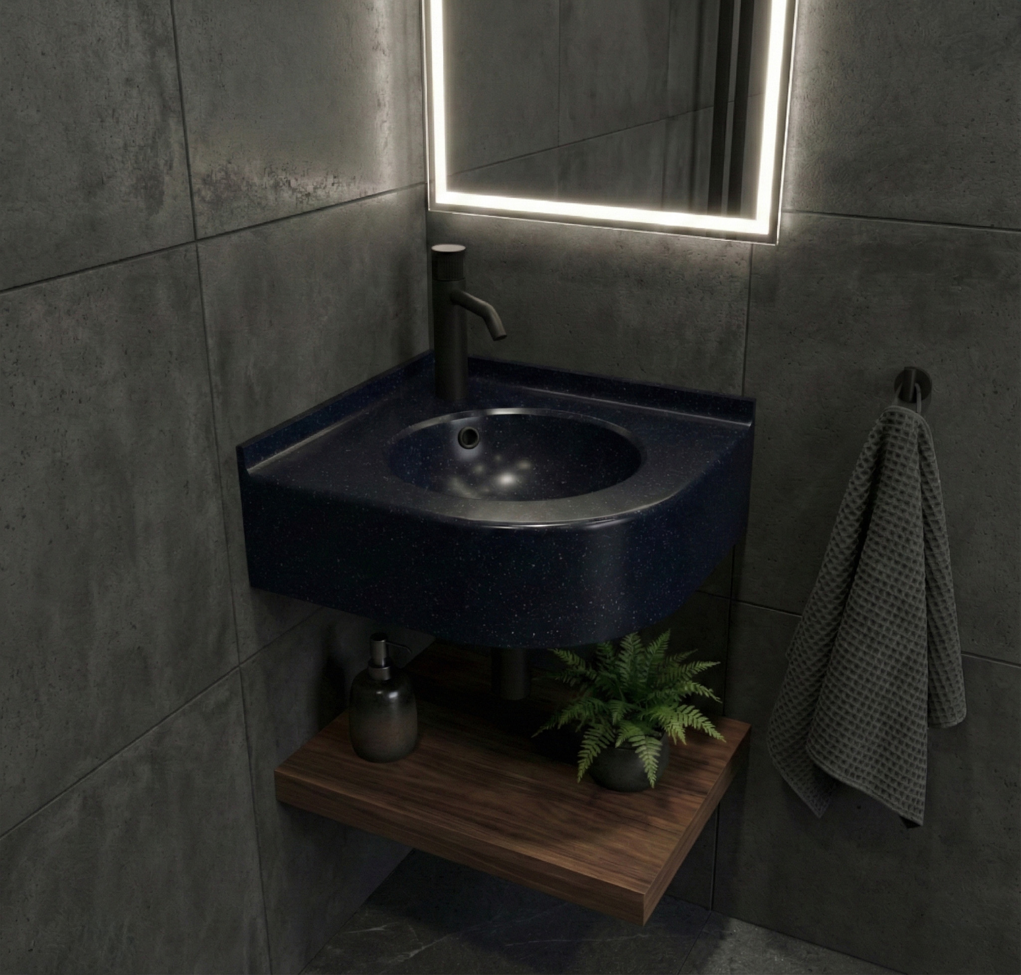 A contemporary bathroom corner featuring a curved corner sink made from Deep Night Sky Corian, showcasing a dark navy surface with white starry speckles. The setup includes a matte black faucet, dark grey stone-textured wall tiles, and a dark wooden floating shelf underneath with towels and a small plant