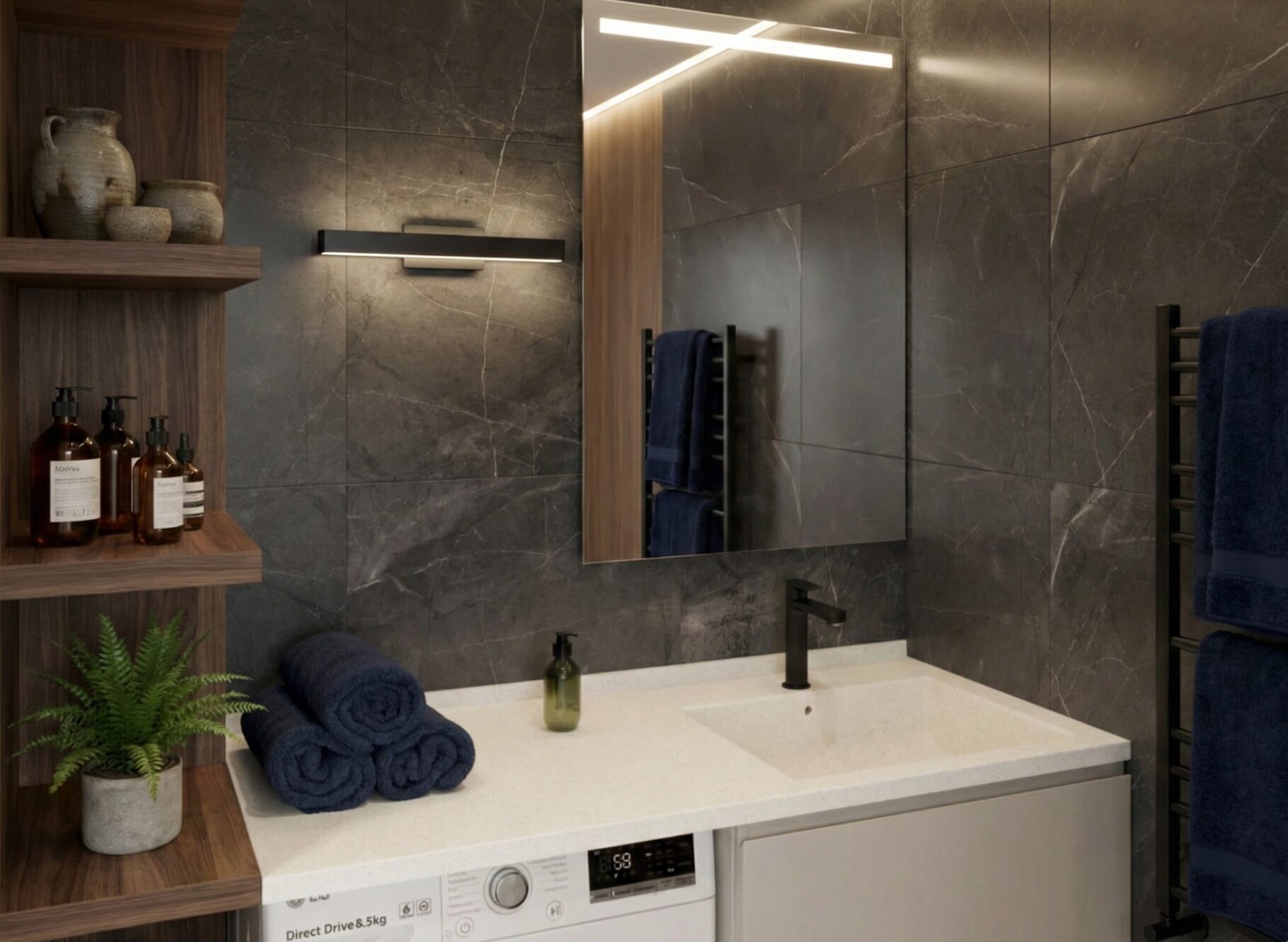 A modern bathroom vanity featuring a white Corian countertop with an integrated sink and black faucet. The counter extends over a washing machine and wooden cabinets. Rolled towels, a potted plant, and a mirror are set against dark grey stone wall tiles